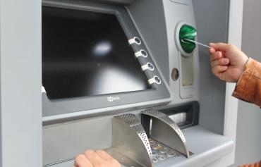 Person, die mit einer Karte an einem Bankautomaten geld abhebt